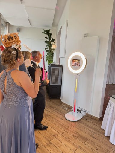 Festlich gekleidete Personen stehen vor einem Fotospiegel mit LED-Rahmen.